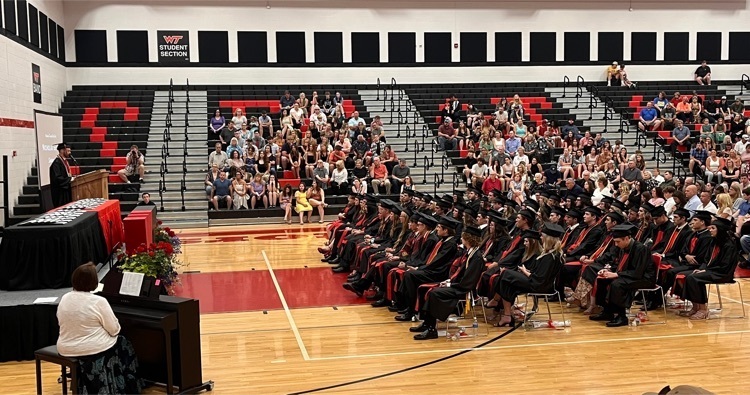 Senior class seated in gym in cap and gown